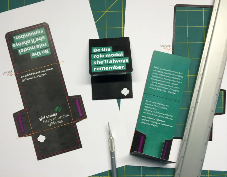 Girl Scouts volunteer marketing materials on crafting table.