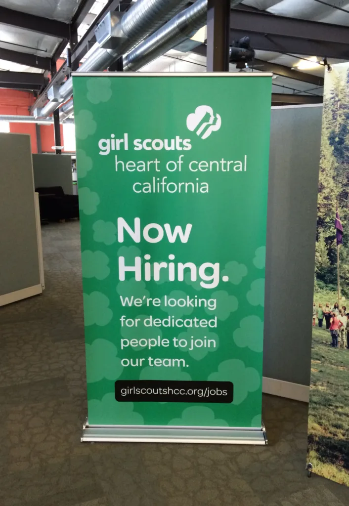 Girl Scouts hiring banner in office setting.