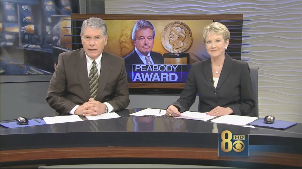 News anchors discussing Peabody Award on TV set.